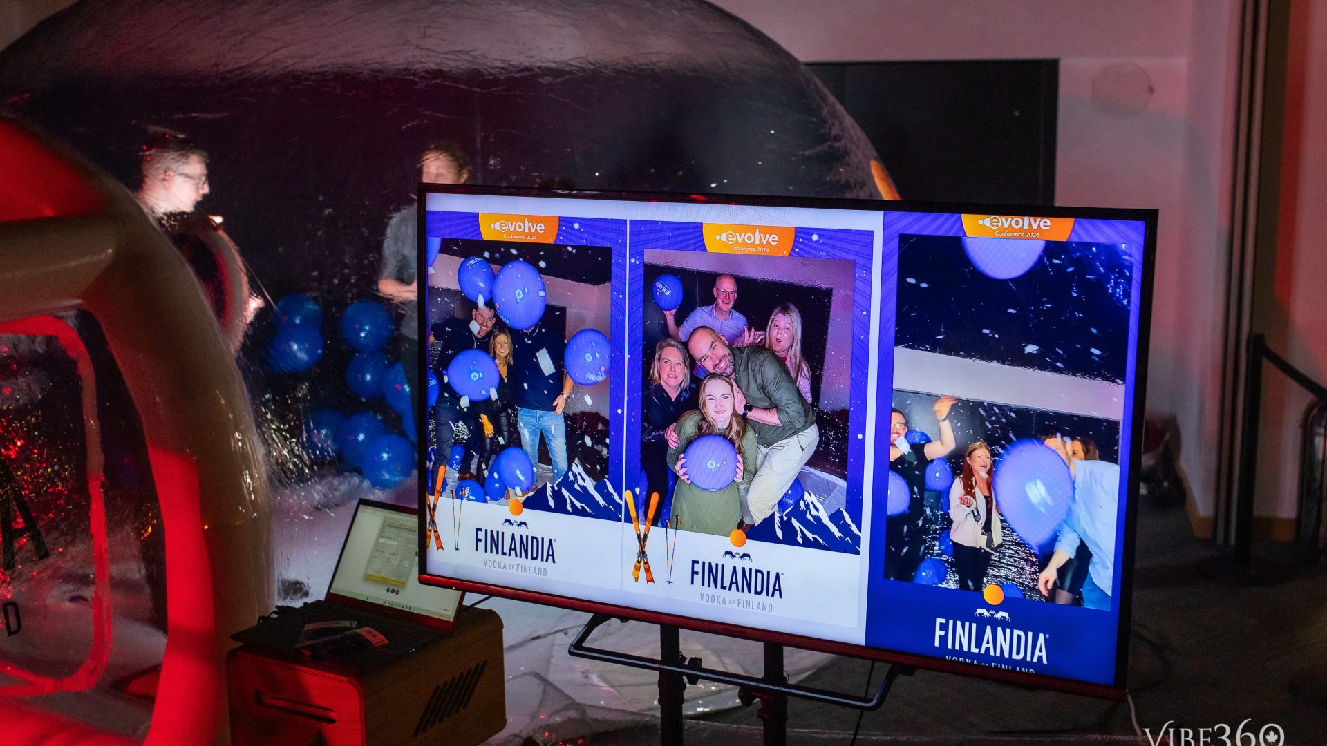 Interactive photobooth event with people, blue balloons, and Finlandia Vodka branding on display screen.