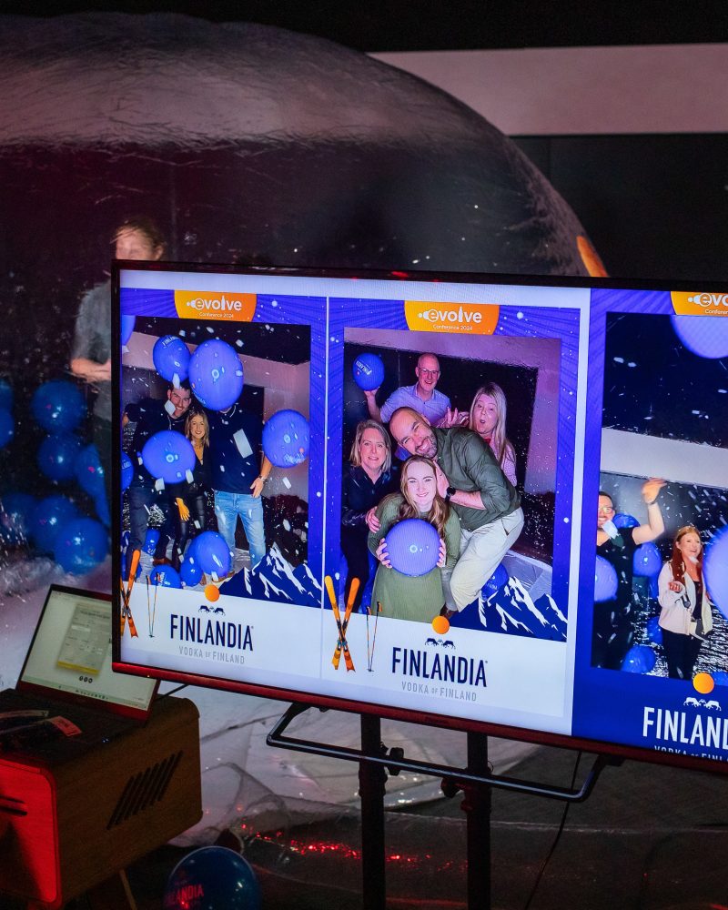 Interactive photobooth event with people, blue balloons, and Finlandia Vodka branding on display screen.
