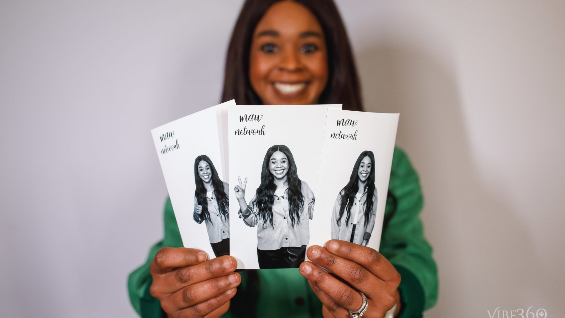Woman holding three photo cards featuring smiling images, promoting the MAV Network.