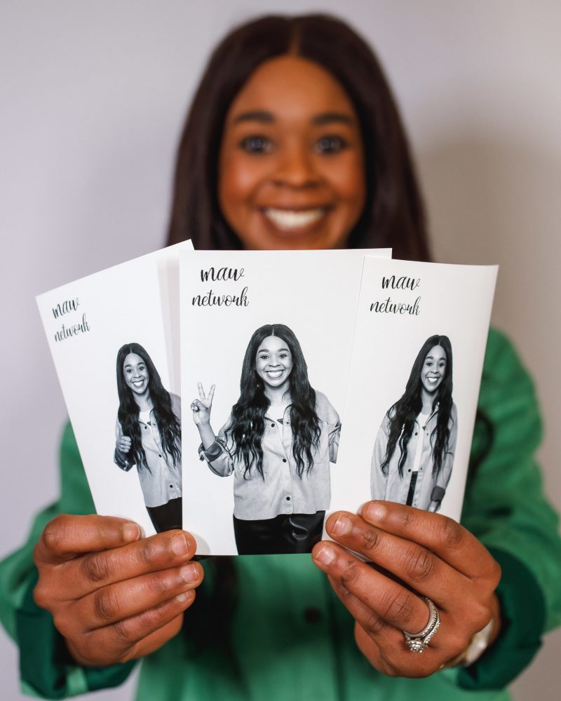 Woman holding three photo cards featuring smiling images, promoting the MAV Network.