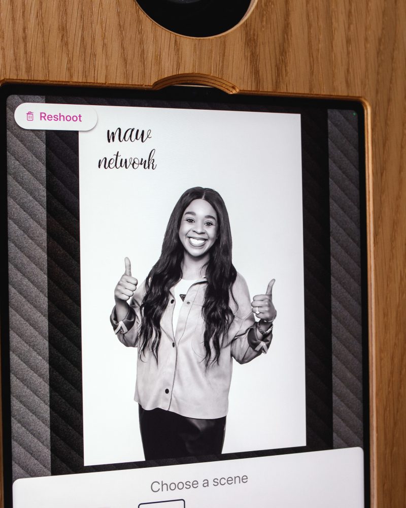 Smiling woman gives thumbs up in a photobooth, displaying 'maw network' logo.