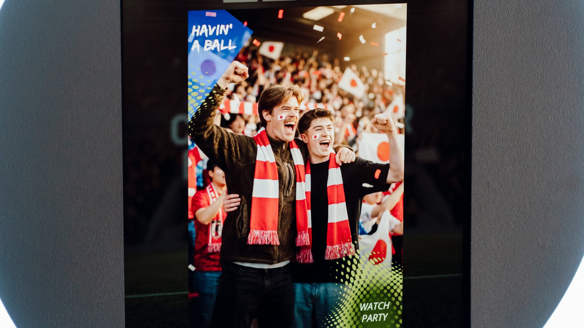 Excited fans at a sports event watch party, wearing red and white scarves, sharing the moment on a digital screen.