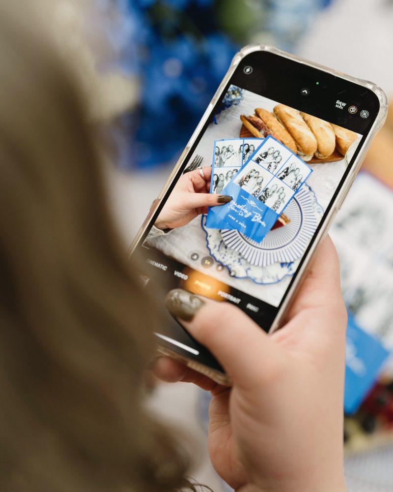 Person photographing event photos and pastries with a smartphone at a celebration.