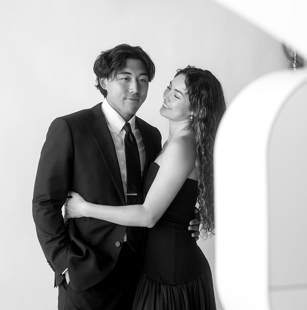 Elegant couple embraces in formal attire during a black-and-white photography session.