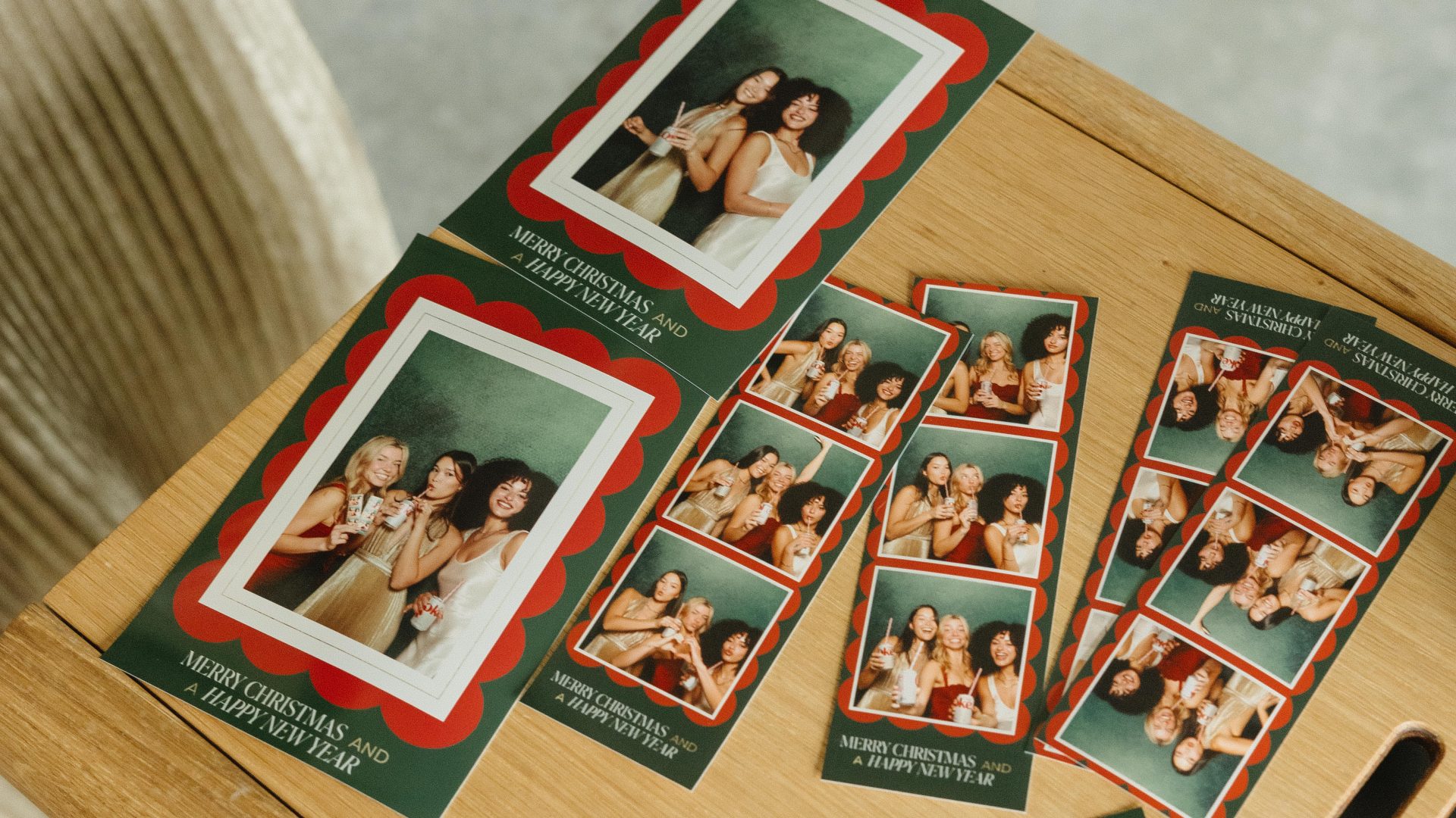 Christmas photo cards with friends celebrating the holidays, featuring festive greetings, on a wooden table.