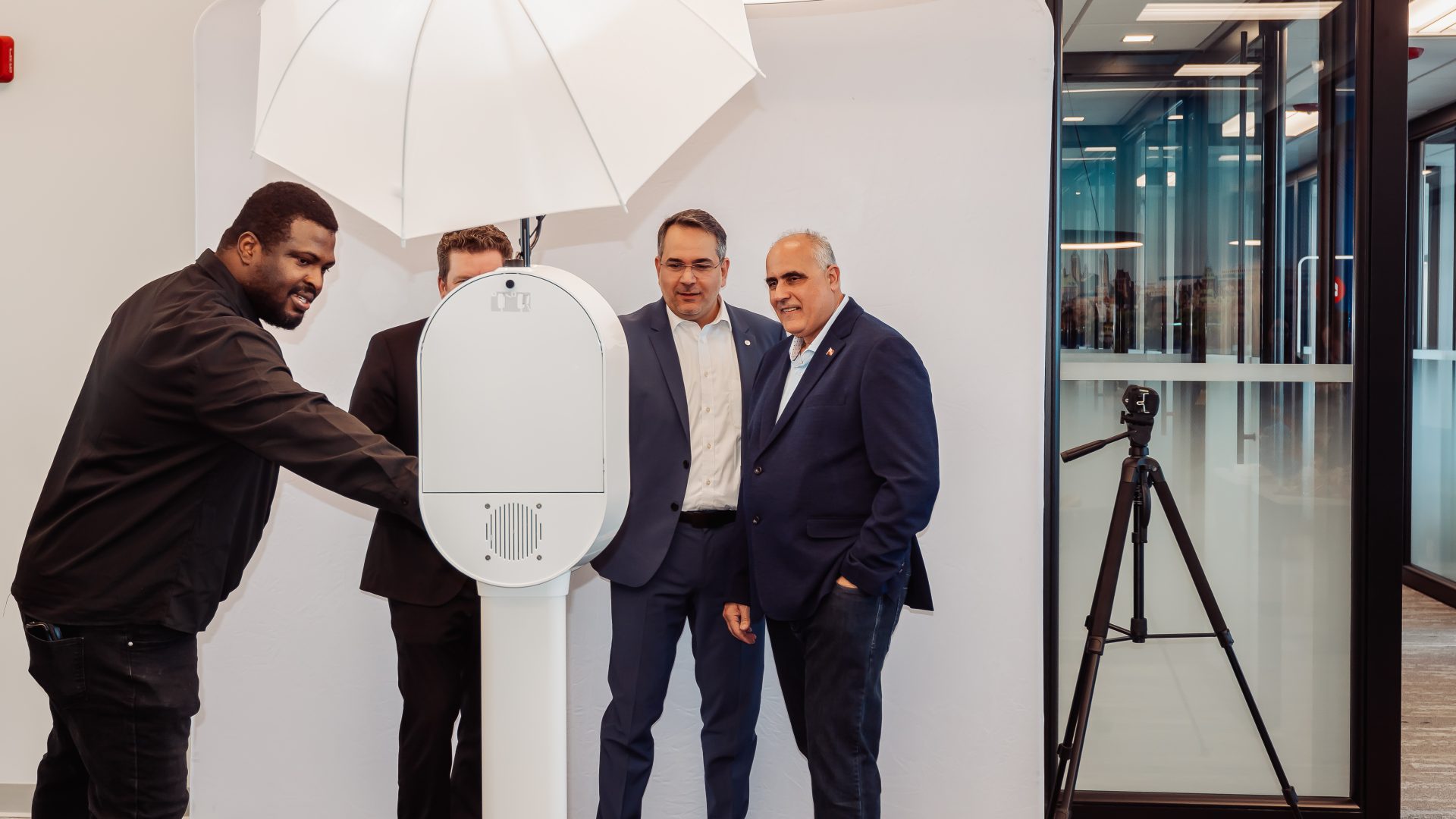 Four men engaged with a photo booth setup, including lighting equipment, in a modern office environment.