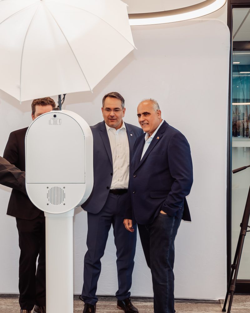 Four men engaged with a photo booth setup, including lighting equipment, in a modern office environment.