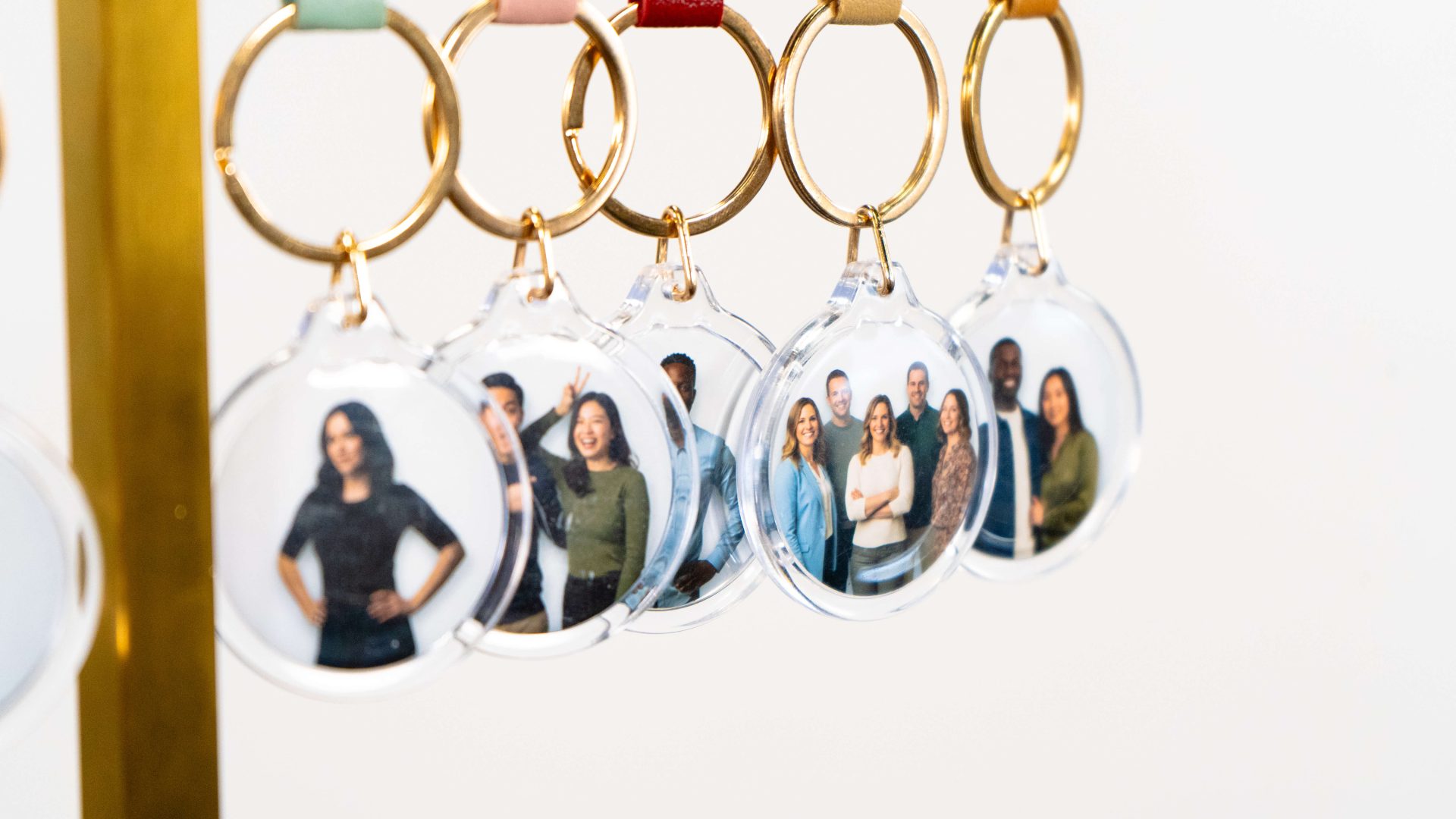 Clear keychains with group photos hanging on hooks with colored leather attachments.