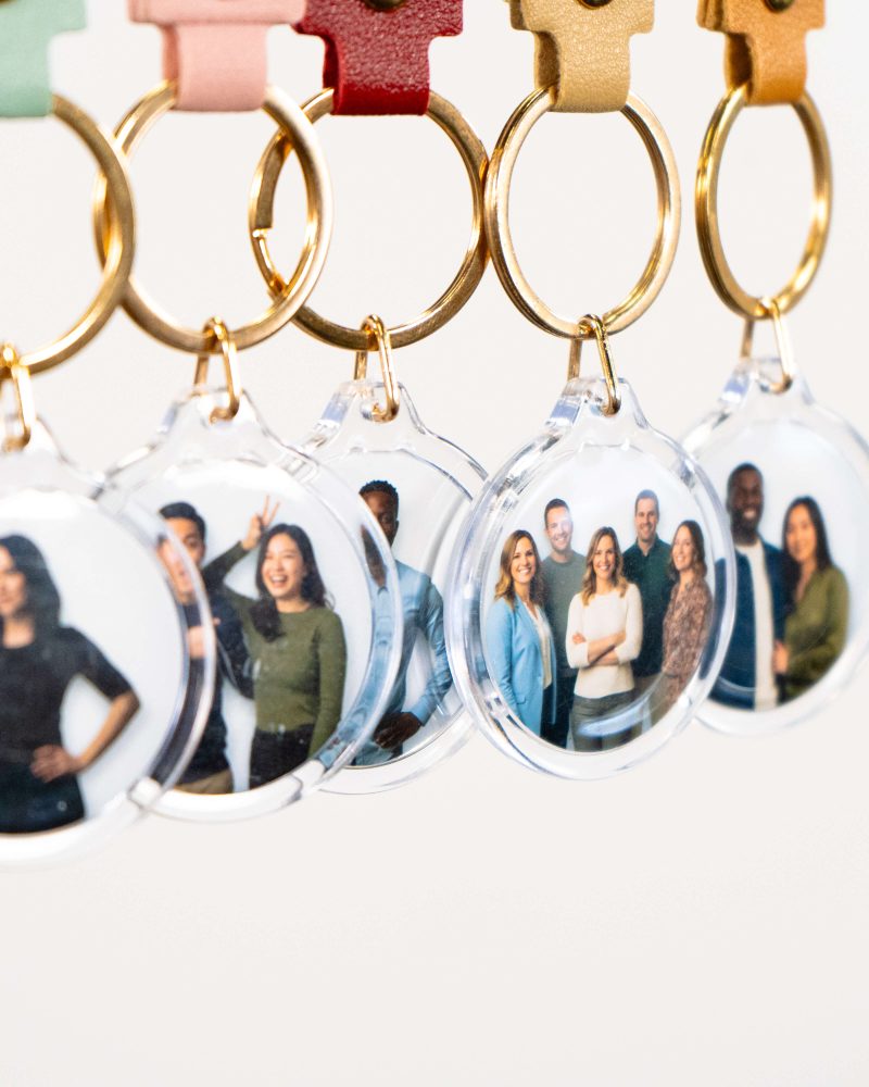 Clear keychains with group photos hanging on hooks with colored leather attachments.