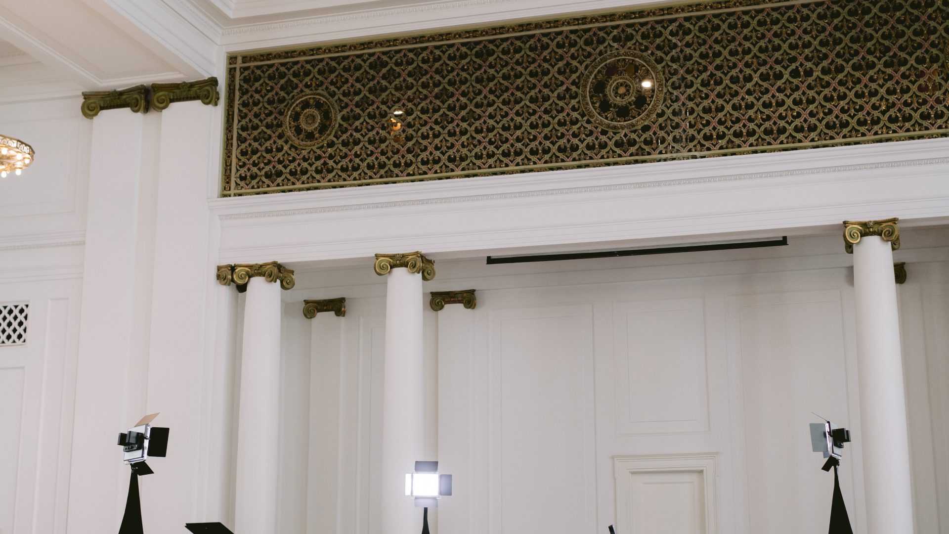 Elegant hall with a grand piano, lighting equipment, and decorative columns, perfect venue for events or concerts.