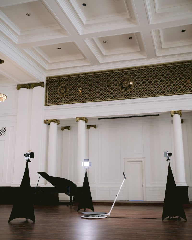 Elegant hall with a grand piano, lighting equipment, and decorative columns, perfect venue for events or concerts.